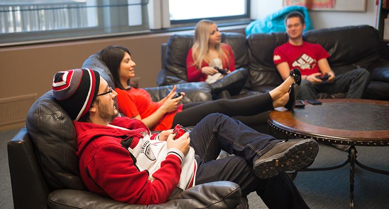 国际学生在沙发上放松，玩电子游戏.